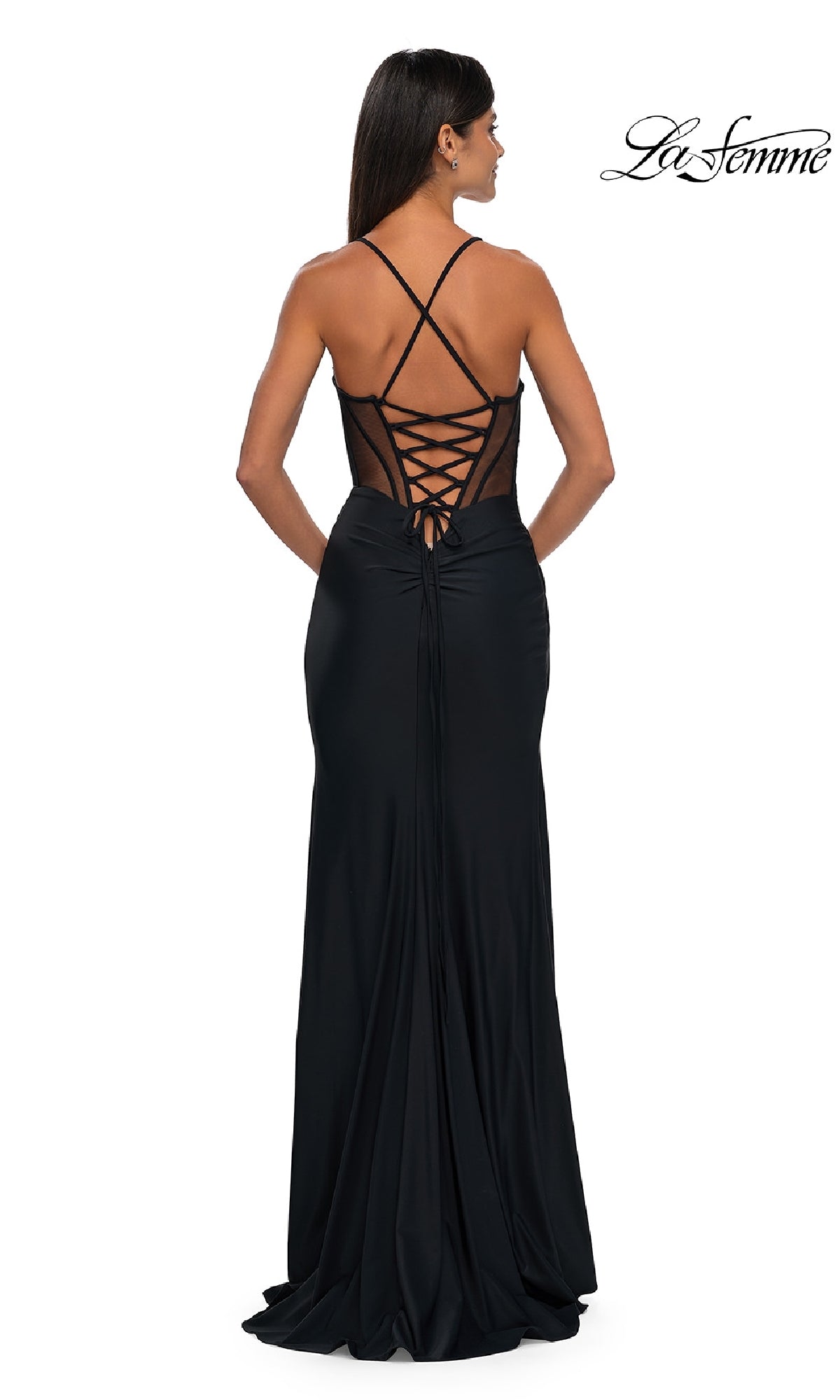 A woman stands facing away from the camera in the La Femme 33115 Strappy-Back Long Black Prom Dress, featuring a crisscross lace-up back and sheer mesh panels.